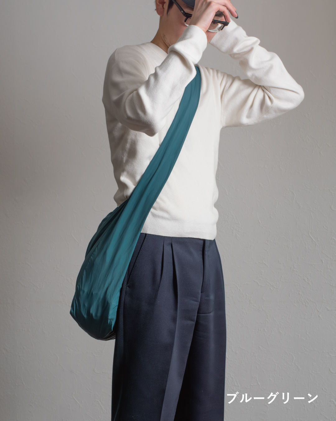 NOMAD SLING(Tav-051)ブラックをストライプシャツに合わせ、斜め掛けした後ろ姿をシンプルに撮影した画像。