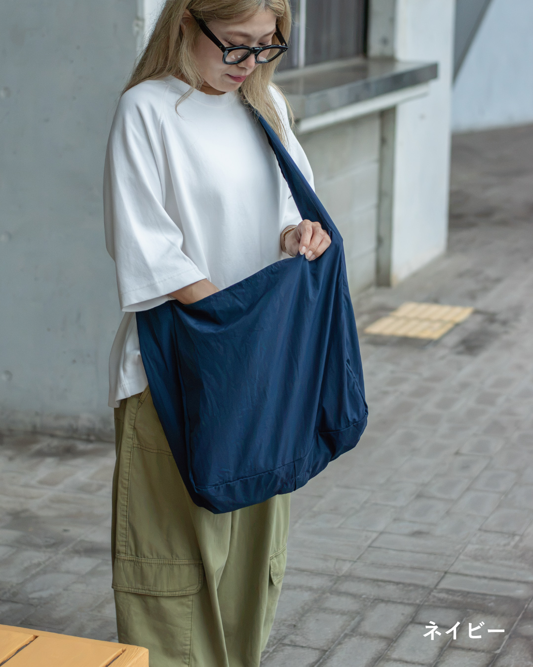 NOMAD SLING(Tav-051)ブルーグリーンを白いニットに合わせ、肩紐部分をクローズアップした着用画像。