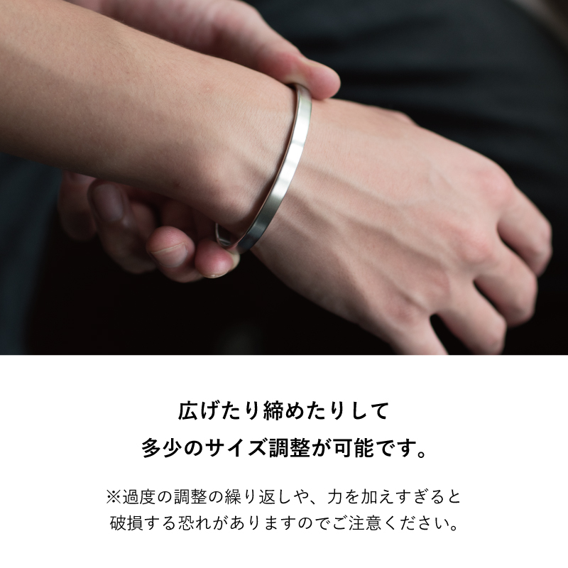 広げたり締めたりして手首に合わせ多少のサイズ調整ができる、TVRT 真鍮バングルを両手で着け外しする様子