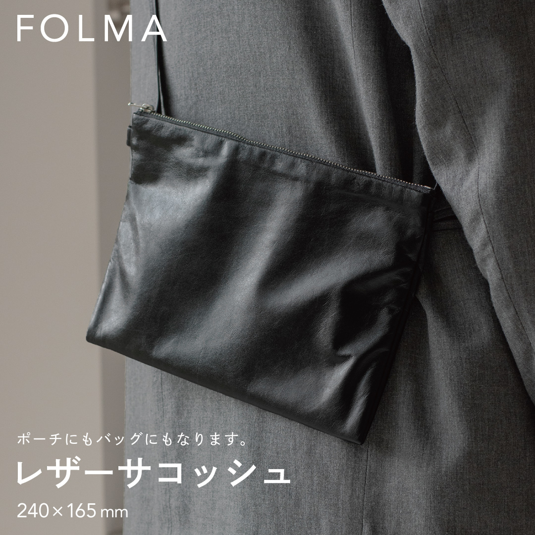 FOLMAレザーサコッシュ（240×165mm）をスーツの脇に斜めがけしたスタイリング。ポーチにもバッグにもなる2WAY仕様のブラックナッパーレザー製サコッシュ。