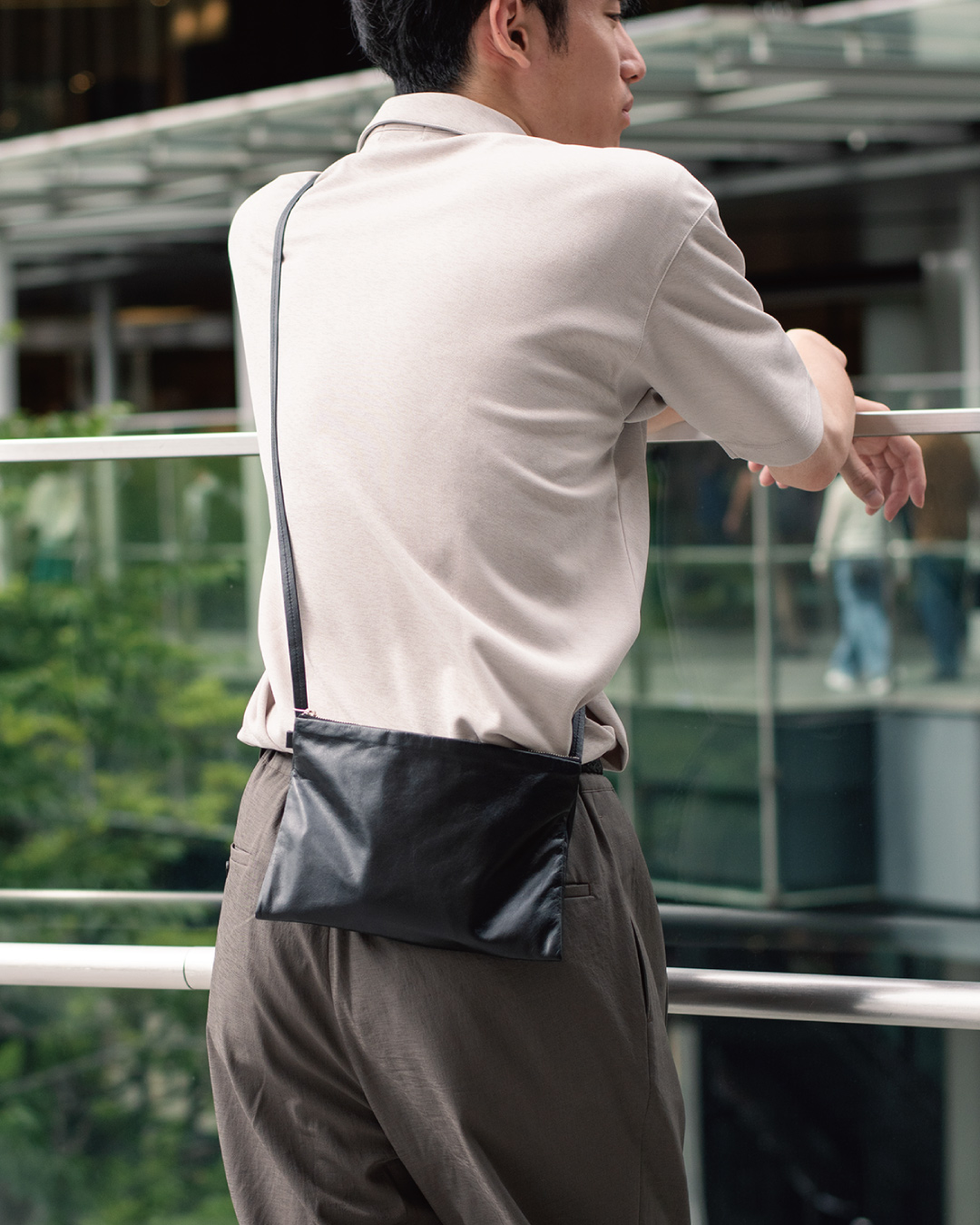 カジュアルな服装でのイメージ画像。都会の街中で背中にサコッシュをかける男性。