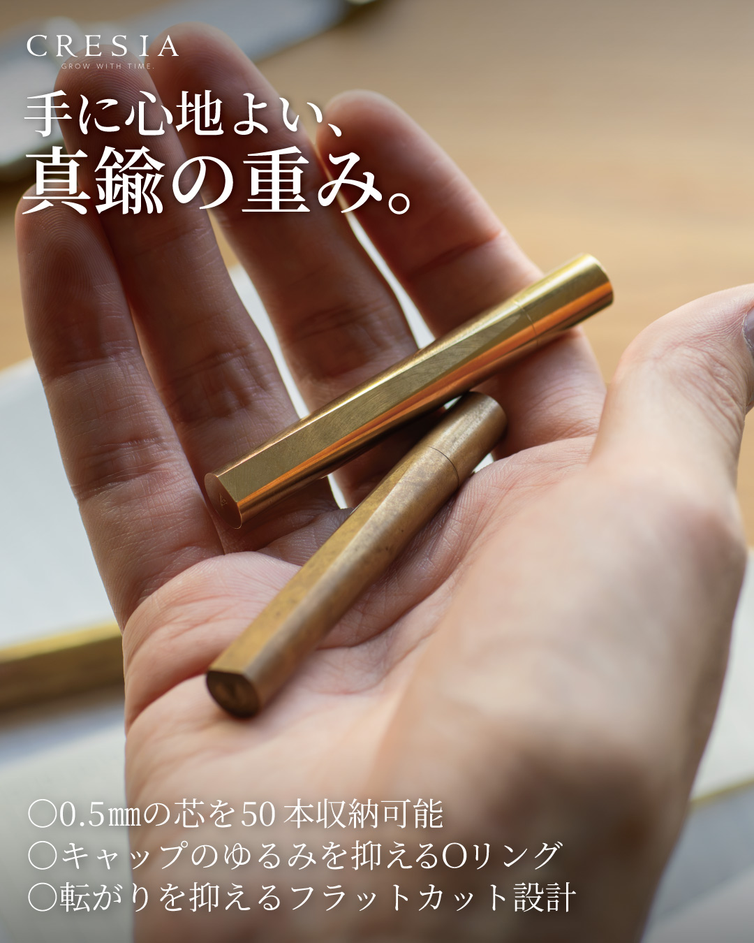 手のひらに乗せた真鍮製のCRESIA シャー芯ケース2本、新品の輝きと使い込んで深まった色合いの比較