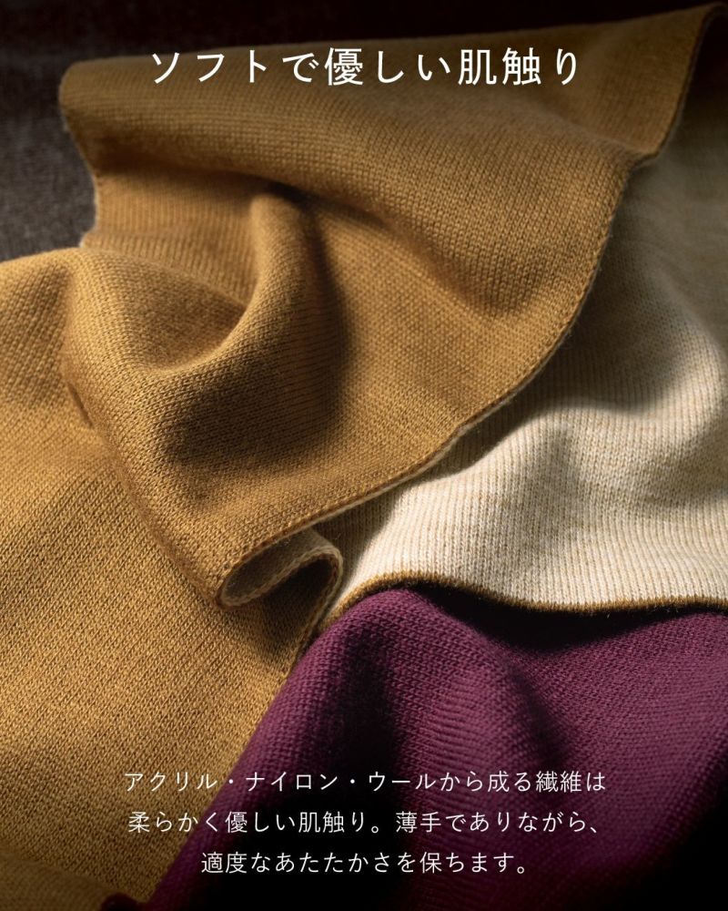 柔らかい肌触りを表現するマフラーのクローズアップ。イエローオーカー、オフホワイト、ワインレッドのマフラーが重ねられている。