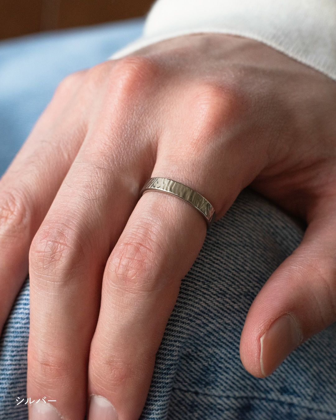 デニムの上に手を置き、シルバーの槌目リングを中指に着用している様子 