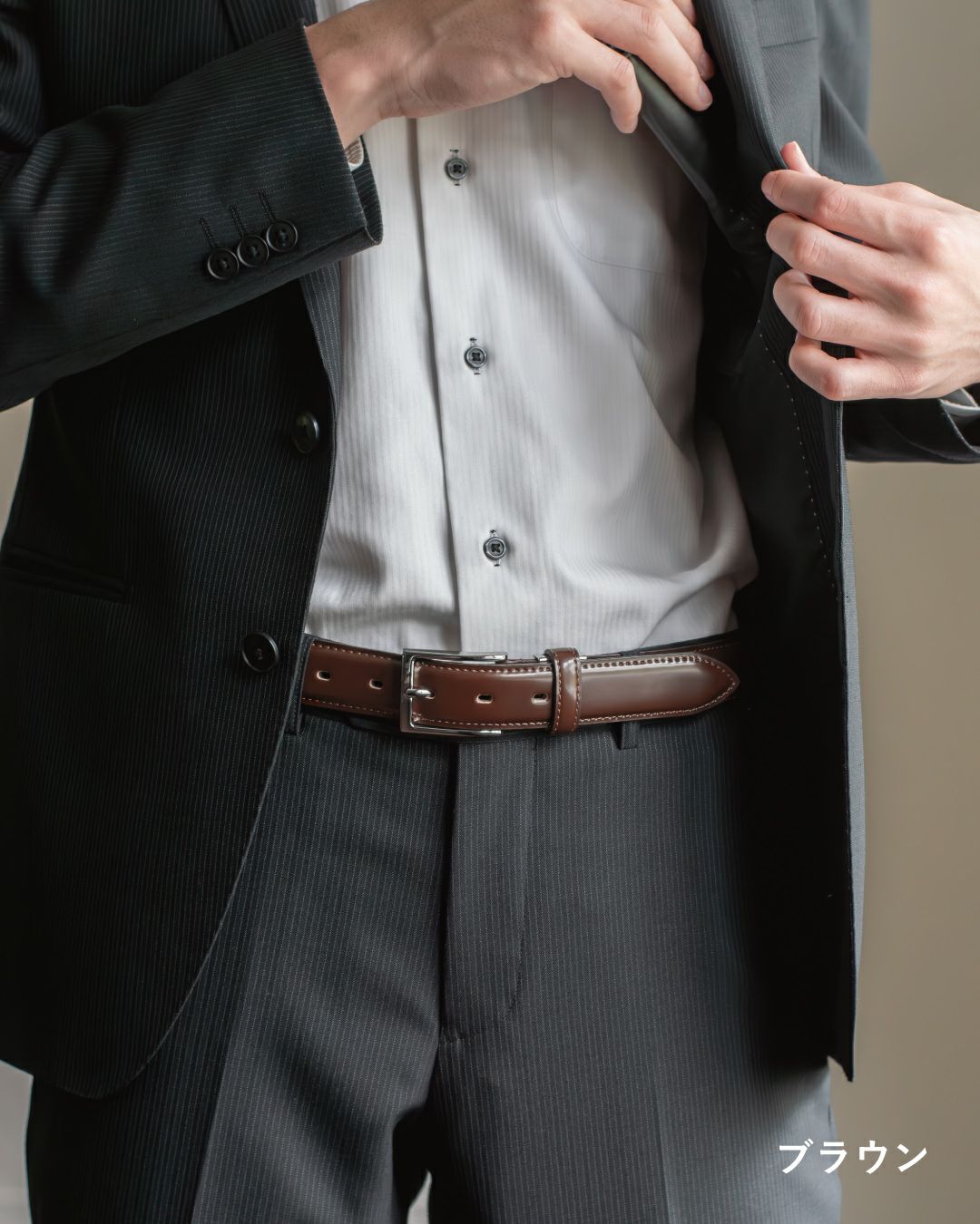 スーツ姿の男性が、ブラウンのコードバンベルトを腰に装着した様子。上質なツヤが際立つシーン。