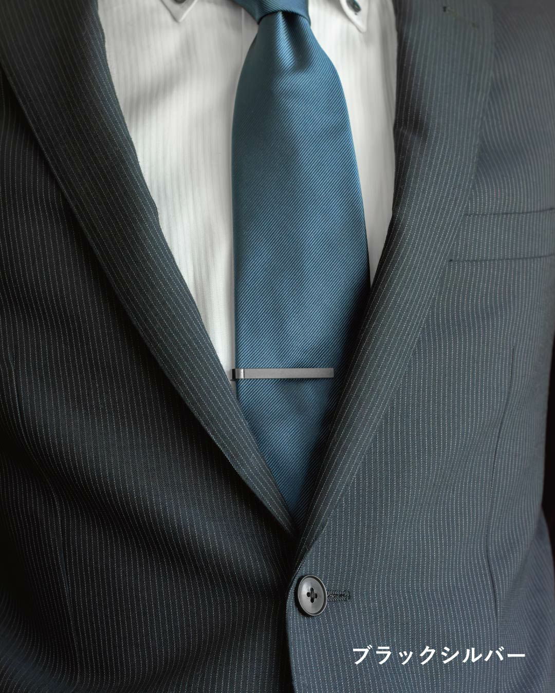 ダークスーツとブルーのネクタイに、ブラックシルバーのネクタイピンを着用した男性の胸元。