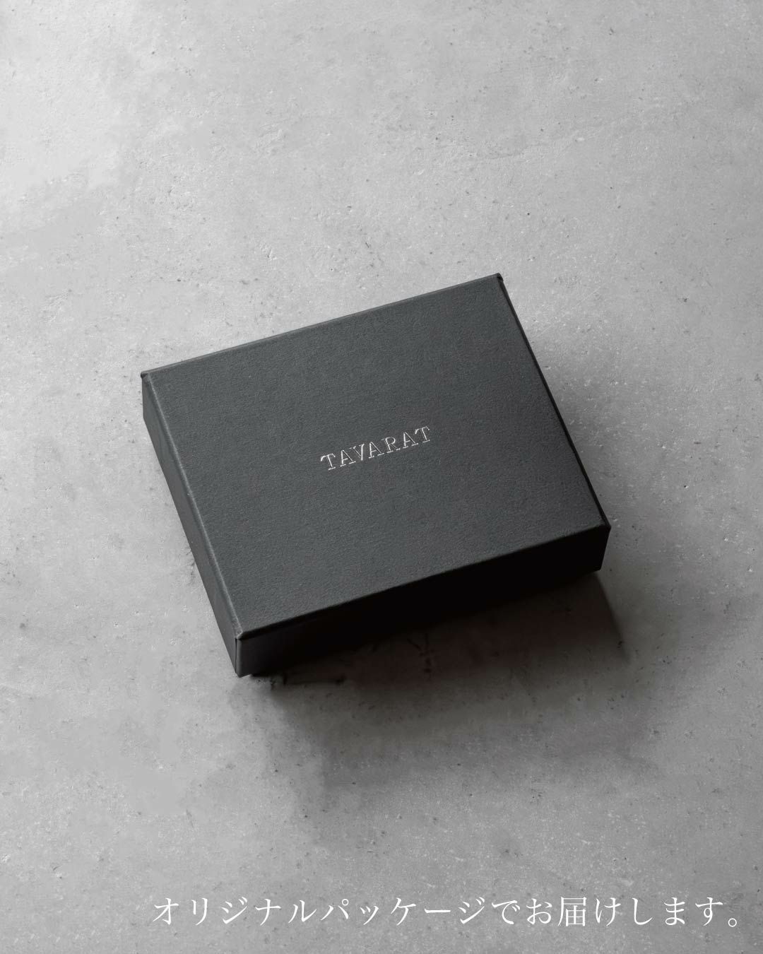 TAVARATのロゴが箔押しされた黒いオリジナルパッケージの箱がコンクリートのような質感の背景に置かれている。ギフトにも適していることが示唆されている。