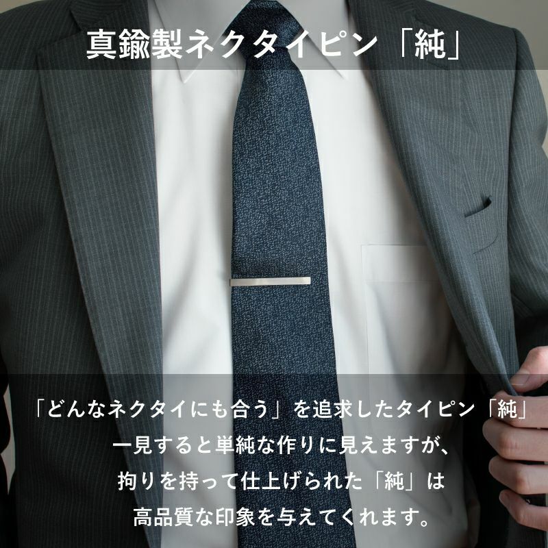 スーツにネイビーのネクタイとシンプルなシルバーのネクタイピンを着用した男性。