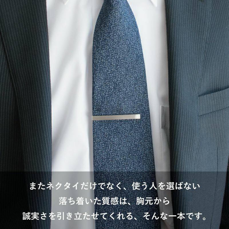 ネイビーのネクタイとシンプルなシルバーのネクタイピンを着用した男性の胸元。