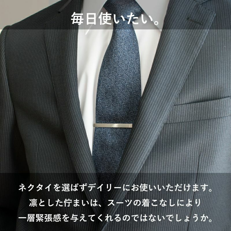 スーツにネイビーのネクタイとシンプルなシルバーのネクタイピンを着用した男性。