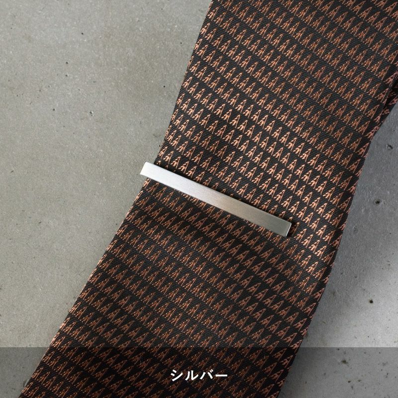 黒地に茶色の柄のネクタイに着用されたシルバーのシンプルなネクタイピン。