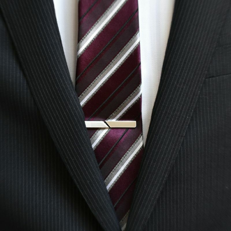 ストライプ柄のワインレッドのネクタイに着用されたシルバーのジオメトリックネクタイピン。