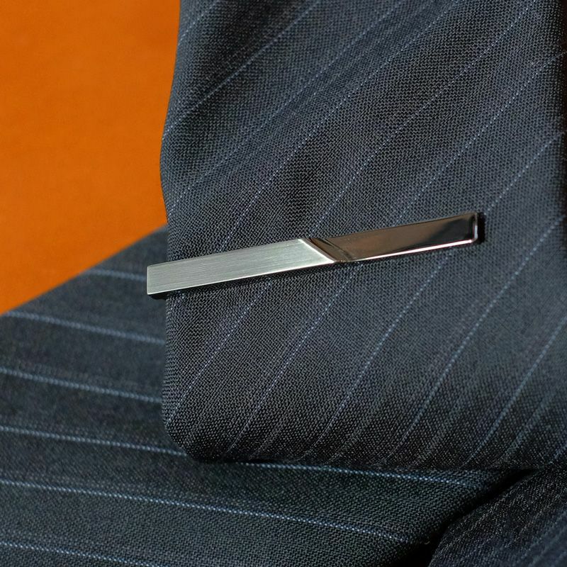 ストライプ柄のネクタイに着用されたシルバーのジオメトリックネクタイピンのクローズアップ。