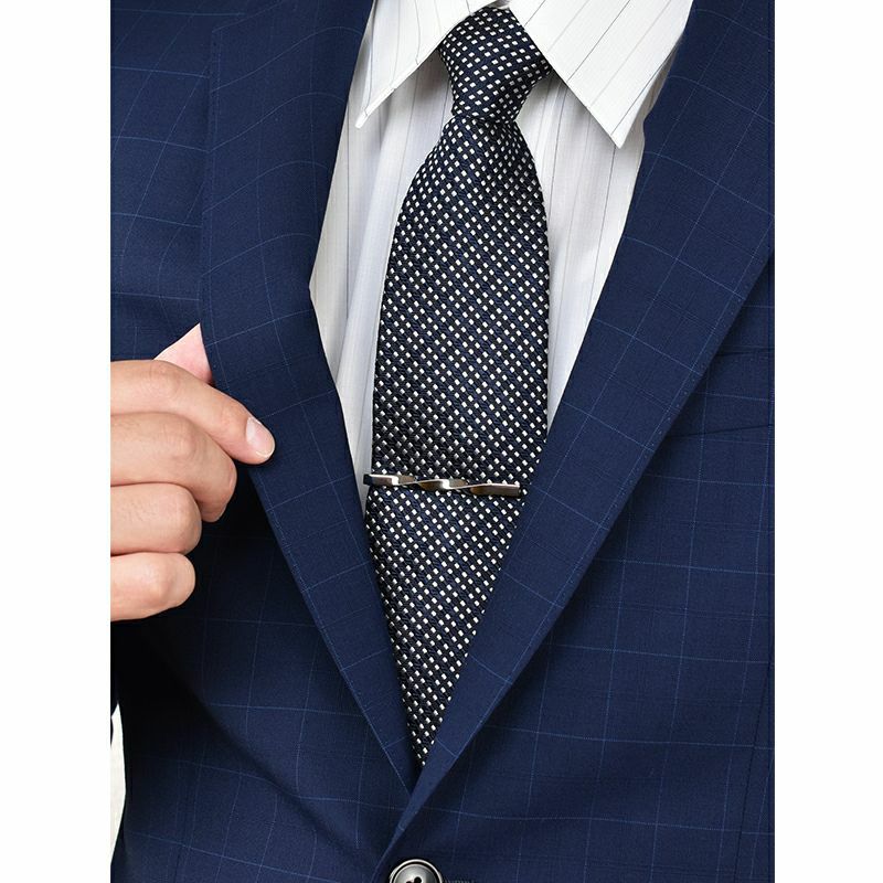 青いチェックのスーツにドット柄のネクタイとシルバーのツイストネクタイピンを着用した男性。