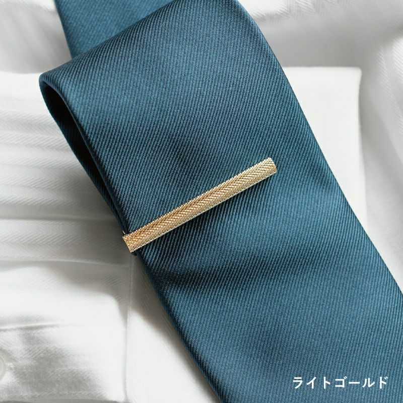 青緑色のネクタイに着用されたライトゴールドのローレットネクタイピン。