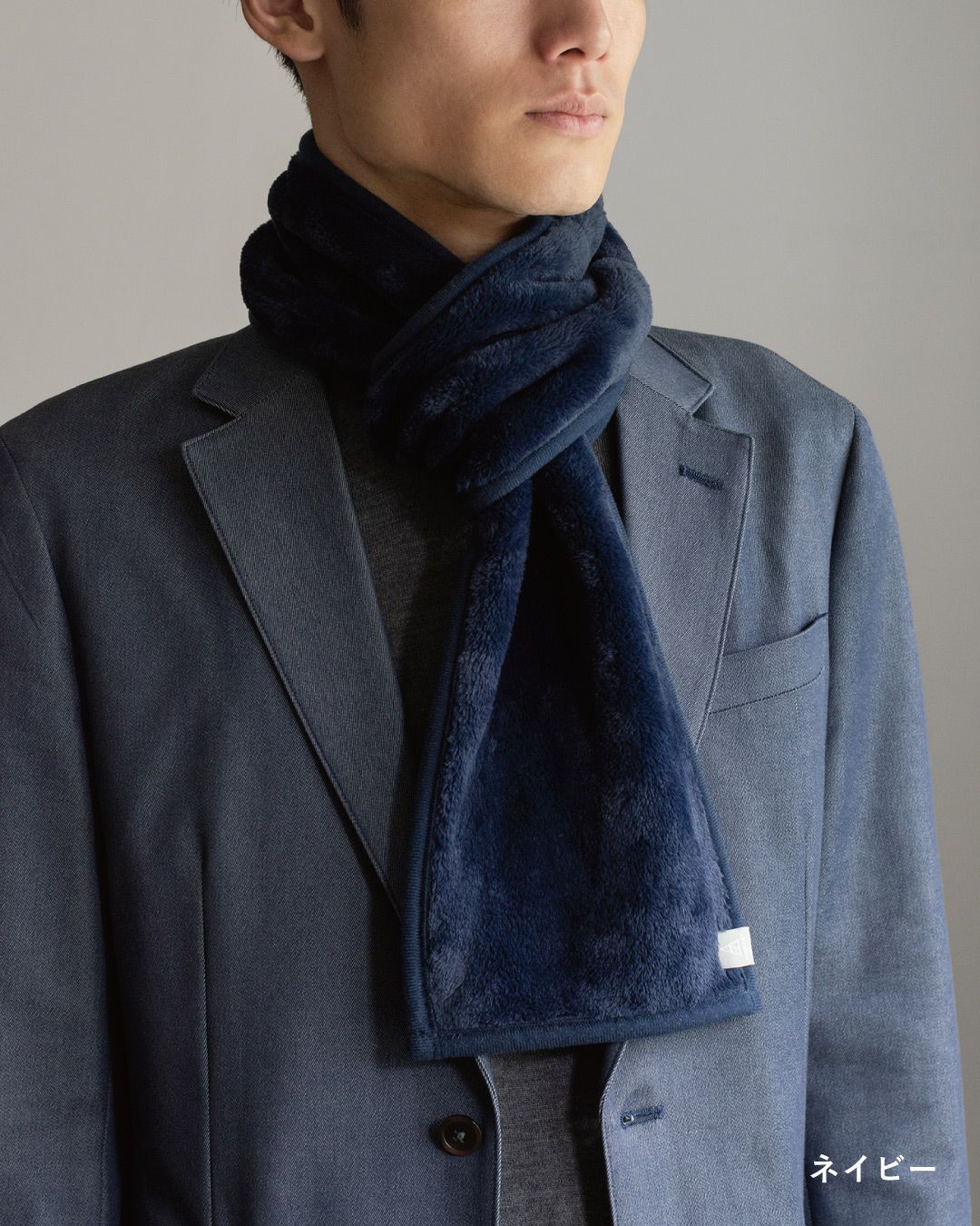 ネイビー色の3秒マフラーを巻いた男性の着こなし。ビジネスシーンやカジュアルに使えるコンパクトマフラー。