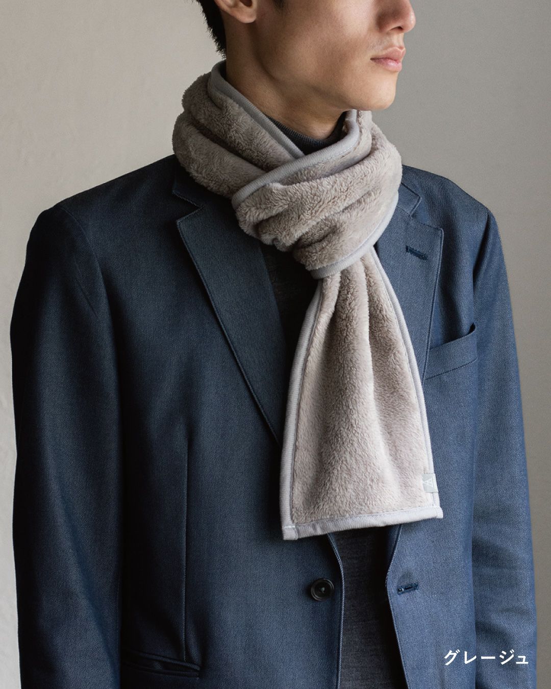 グレージュ色の3秒マフラーを巻いた男性の着こなし。顔周りを明るく見せるフリースマフラー。