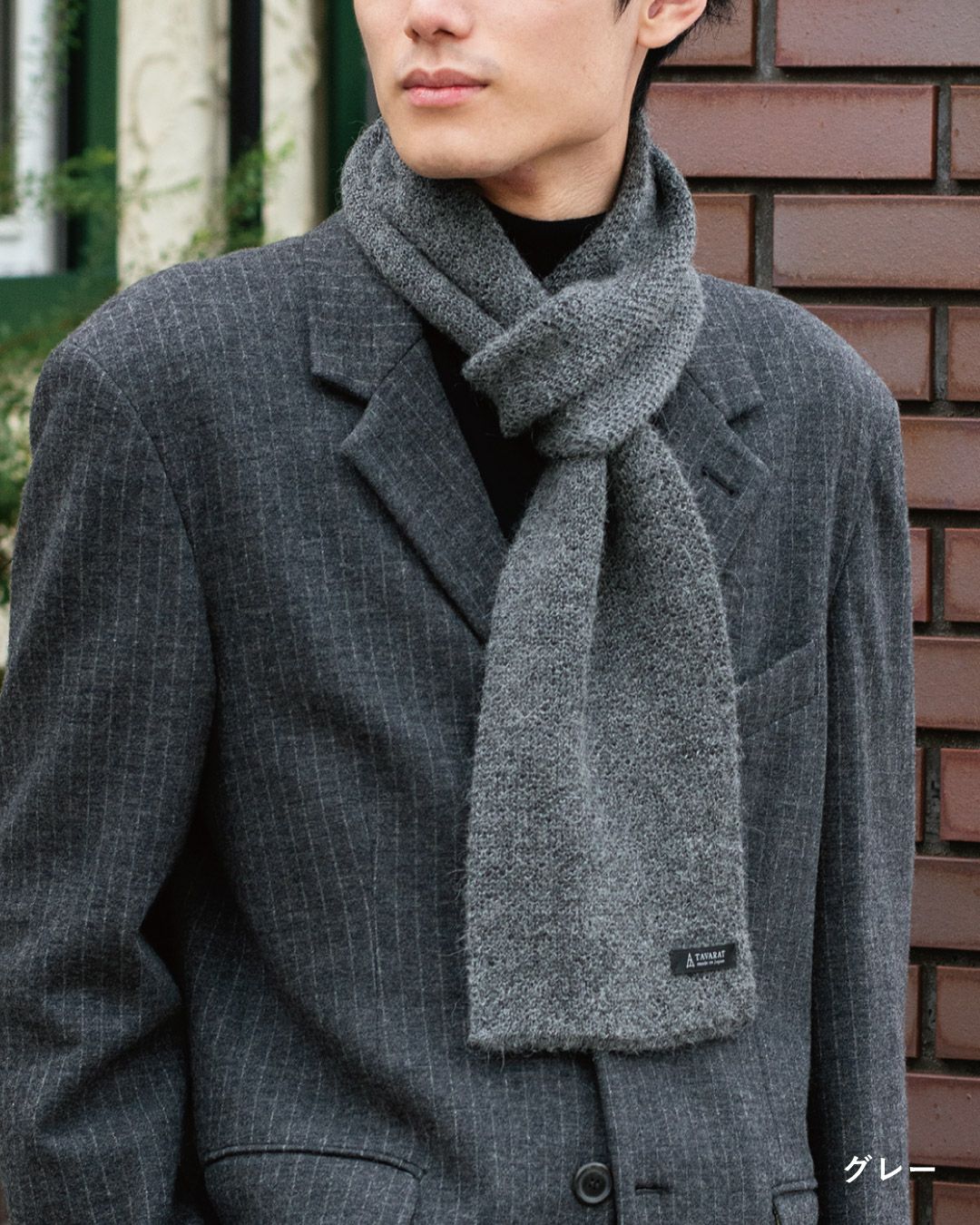 グレー色のアルパカ100%マフラーを巻いた男性の着こなし。シックな色味でスーツに合わせやすいビジネスマフラー。