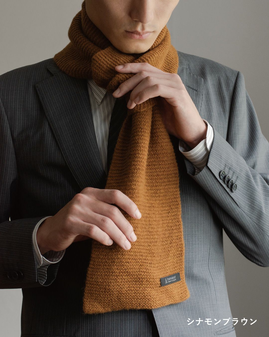 シナモンブラウン色のタック編み 3秒マフラーを巻いた男性の着こなし。暖かみのある色でスーツにアクセントを加える。