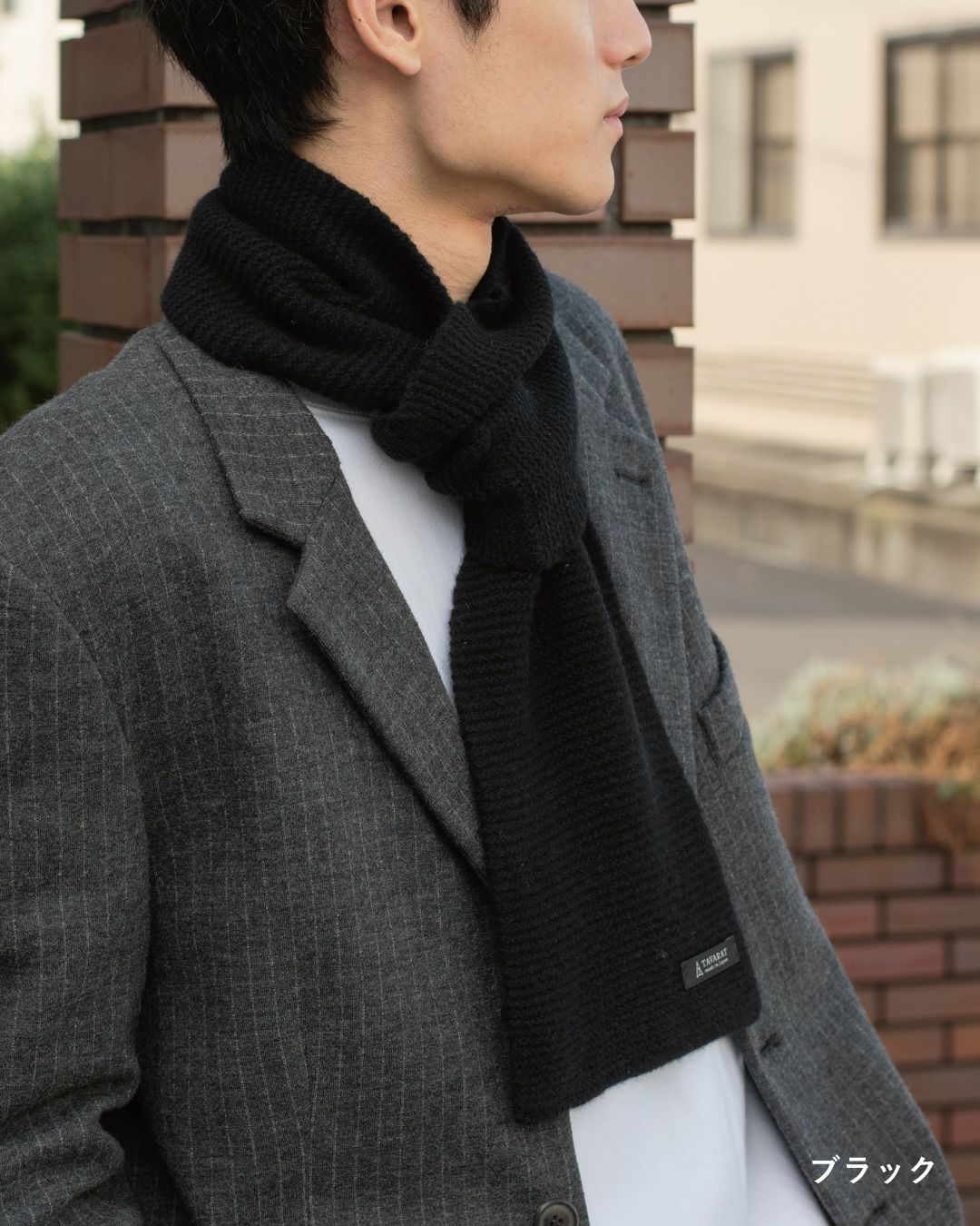 ブラック色のタック編みマフラーを巻いた男性の着こなし。フォーマルにも使えるラムウール混紡マフラー。
